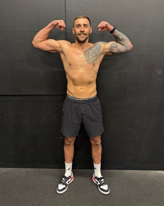 Lewis flexing against a dark wall